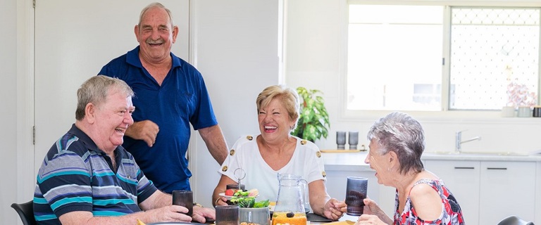 A group of seniors sitting around the coffee table laughing A group of seniors sitting around the coffee table laughing