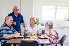 A group of seniors sitting around the coffee table laughing A group of seniors sitting around the coffee table laughing